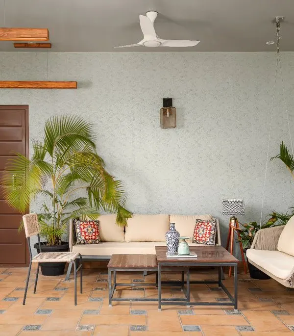 This covered patio on a terrace is designed as an extension of the living room. With terracotta tiles, comfortable seating, and surrounding plants, it's a perfect spot for relaxing or entertaining.