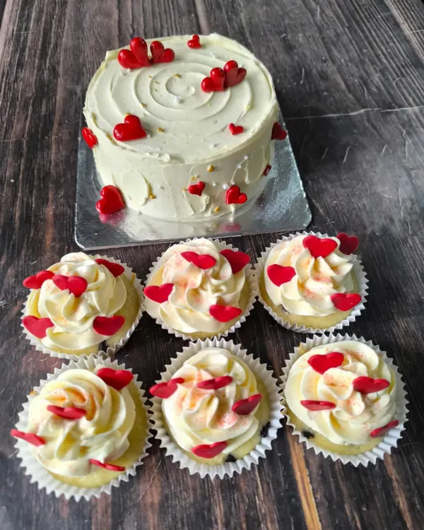 The season of love. This set includes a simple heart-themed cake and six matching cupcakes, all decorated with vanilla buttercream and tiny red hearts.