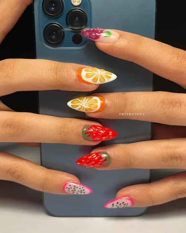 A different view of the fruit salad nails, posed against a phone to show how vibrant the colors are. Each fruit is a tiny, hand-painted masterpiece.