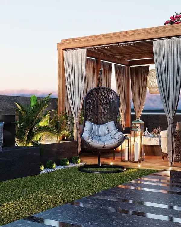 A luxurious terrace design featuring a wooden pergola with curtains for privacy, a tranquil Buddha statue with a water feature, and comfortable seating. This render sells an aspirational lifestyle.