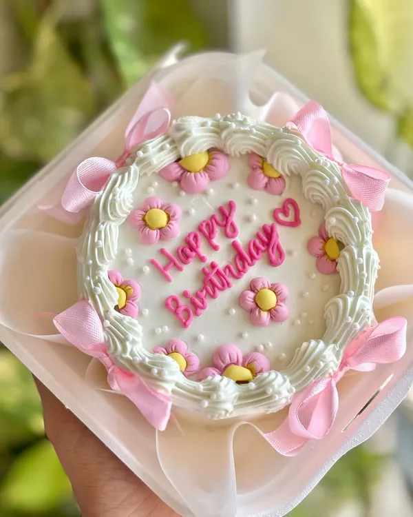 Mini dreams in pastel hues. This balletcore bento cake features soft off-white, pink, and yellow florals with delicate ribbons, perfect for an aesthetic birthday gift.