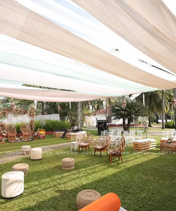 This wide view showcases a complete boho-themed outdoor Mehndi setup. We used a mix of rattan chairs, low poufs, and wooden crate tables under a flowing fabric canopy to create a relaxed and stylish lounge area for guests.