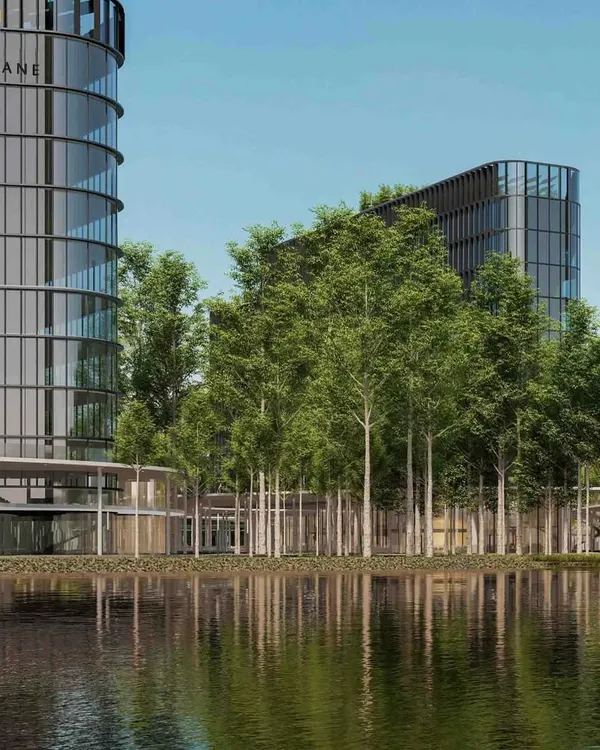 A view of a modern tech campus where glass towers rise from a forest-inspired landscape. The large water feature in the foreground not only adds serenity but also creates a natural boundary between the public and private zones of this mixed-use development.