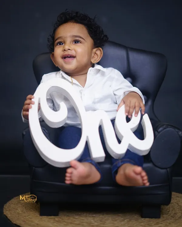 He is ONE. A classic first birthday portrait with the baby sitting in a miniature armchair, holding the "ONE" sign. Simple, elegant, and timeless.