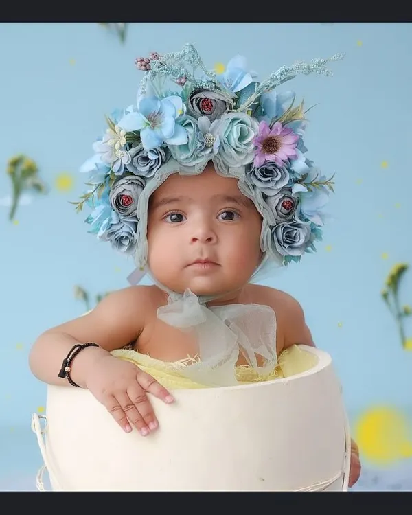 This little one looks so curious, peeking out of a white bucket while wearing an intricate blue floral bonnet. Sitter sessions are perfect for capturing these inquisitive and adorable expressions.