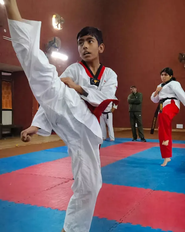 A young Taekwondo student practices a high side kick with precision and focus during a class. Notice his form and balance, key elements we develop in our youth martial arts programs.