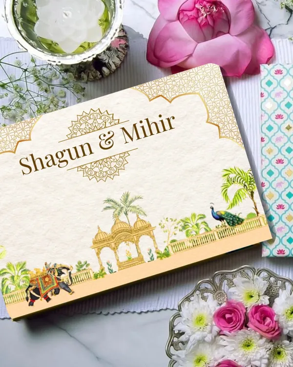 This is the top of the custom 'Shagun & Mihir' invitation box, featuring a royal Indian theme with intricate gold details, peacocks, and illustrated elephants. It sets the tone for a grand and traditional wedding celebration.