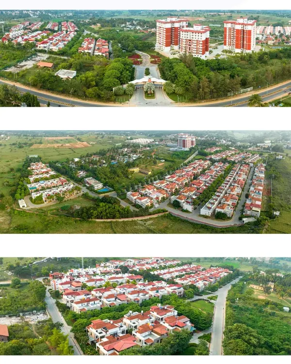 A wide aerial shot of the entrance to Zuari Garden City, showing the relationship between the apartment towers, villa community, and surrounding green landscape.