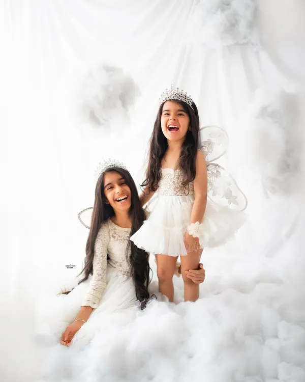Pure joy and laughter between two angelic sisters, playing in a sea of fluffy clouds. These sibling photoshoots are filled with magical moments.