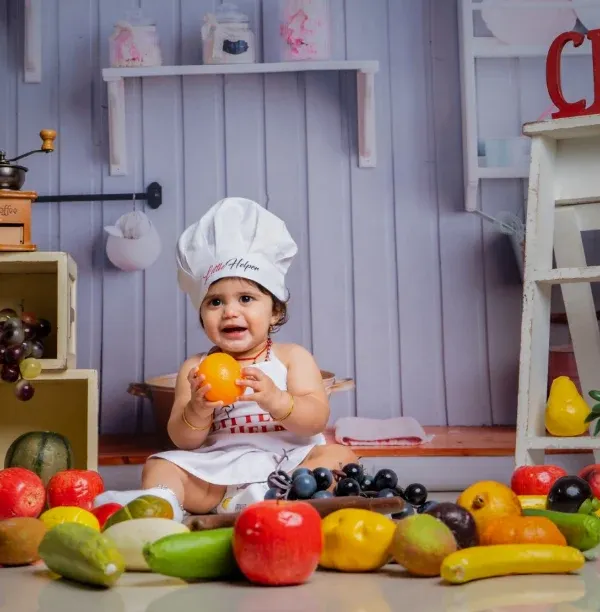 Meet the tiniest chef in town, serving cuteness with a sprinkle of giggles and a side of fruits.