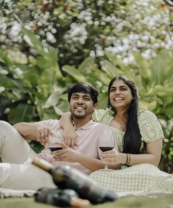 A relaxed and happy pre-wedding picnic. This shot captures the couple enjoying a glass of wine and each other's company in a beautiful, natural setting, showcasing their easygoing connection.