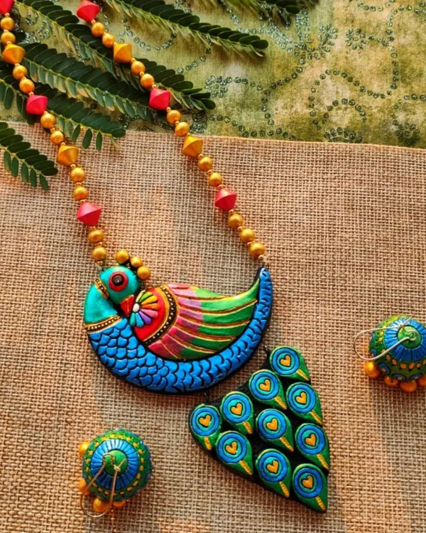 This artistic peacock necklace is one of my signature creations, a piece I am incredibly proud of. I meticulously sculpt and paint each feather detail with metallic hues to create a vibrant, textured look. The set includes matching jhumka earrings, making it a complete statement piece for any celebration.
