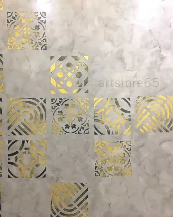 A close-up of the metallic gold stencils on a grey textured base. You can see how the light catches the different patterns, creating a dynamic and luxurious effect for this bedroom wall.