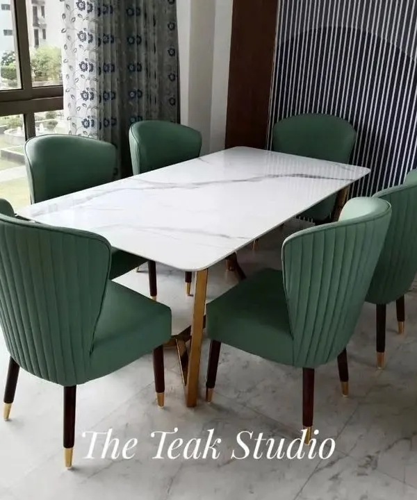 A beautiful six-seater set featuring a white marble tabletop with subtle grey veining. The plush, channel-tufted green velvet chairs add a pop of color and sophistication, while their tapered legs with gold-finished tips complete the luxurious look.