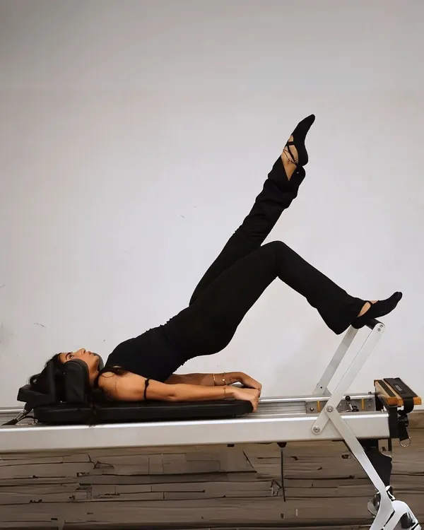 The reformer isn't just a machine, it's a full-body wake-up call. This client is performing a shoulder bridge with leg extension, a move that strengthens the entire back of the body.