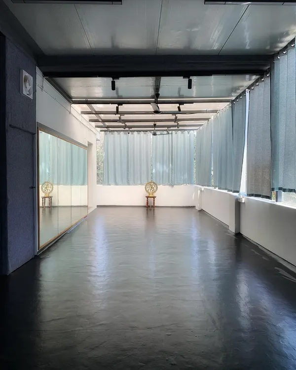 A view of our main practice hall, where natural light fills the room. The full-length mirrors help you refine your alignment and posture during our yoga sessions.