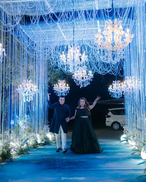 The grand entrance to a sangeet under the stars. Guests walked through a tunnel of shimmering blue light and crystal strings, flanked by chandeliers, setting the tone for a magical night at Oleander Farms.