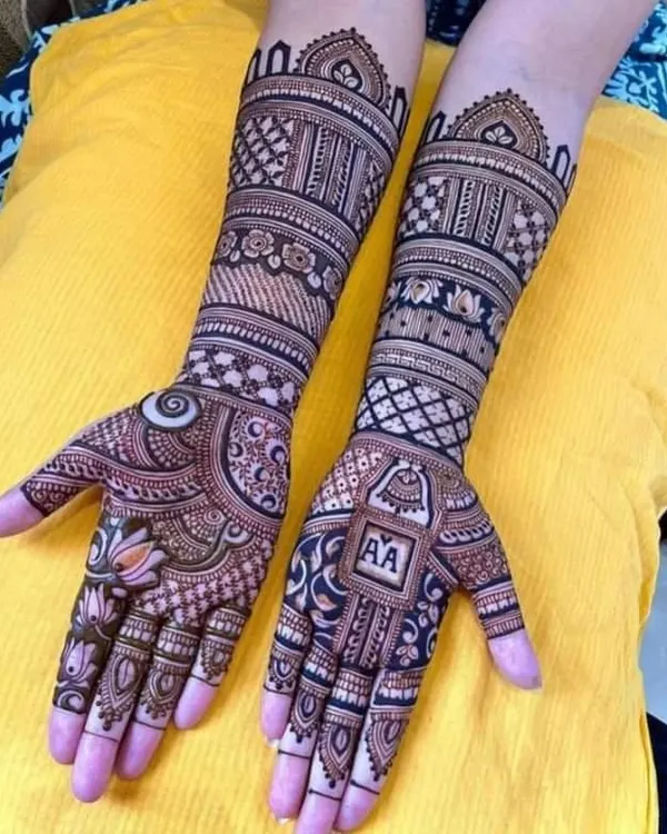 A perfect example of a personalized engagement mehandi. This design features the couple's initials "AA" in a neat block on one hand, balanced with a lotus motif on the other.