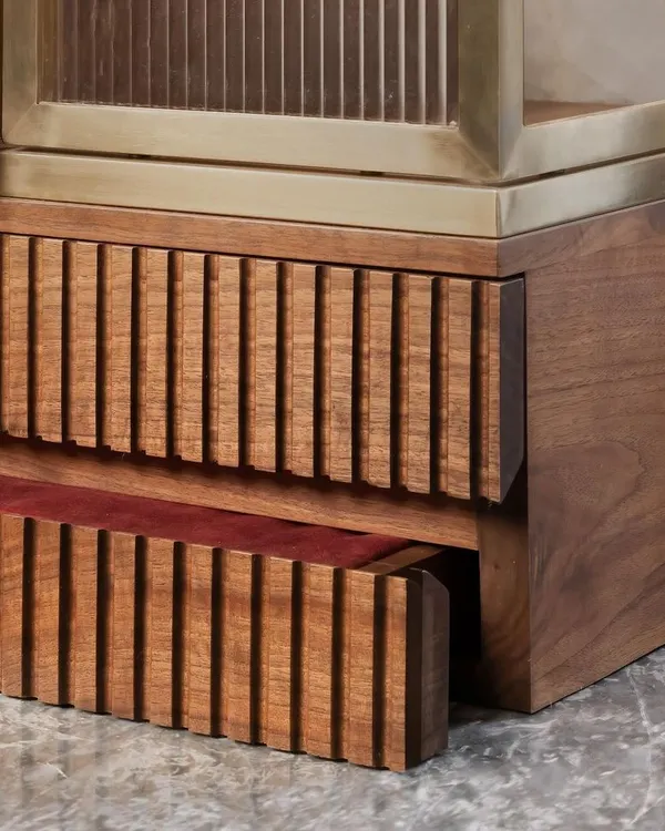 A well-crafted detail is a joy to discover. This image shows the fine fluting on a solid wood drawer, which contrasts beautifully with the smooth brass frame and the rich walnut of the main cabinet.