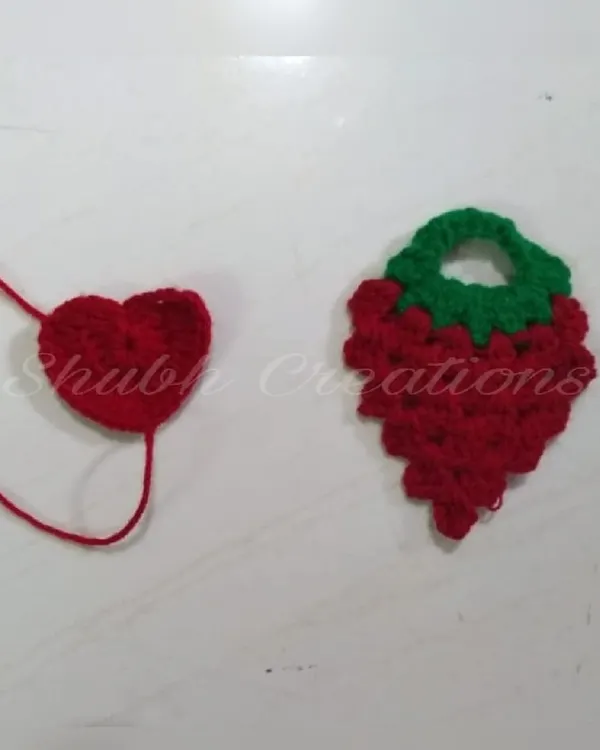 Two small crochet appliqués, a simple red heart and a strawberry top, showing how I create small decorative elements.