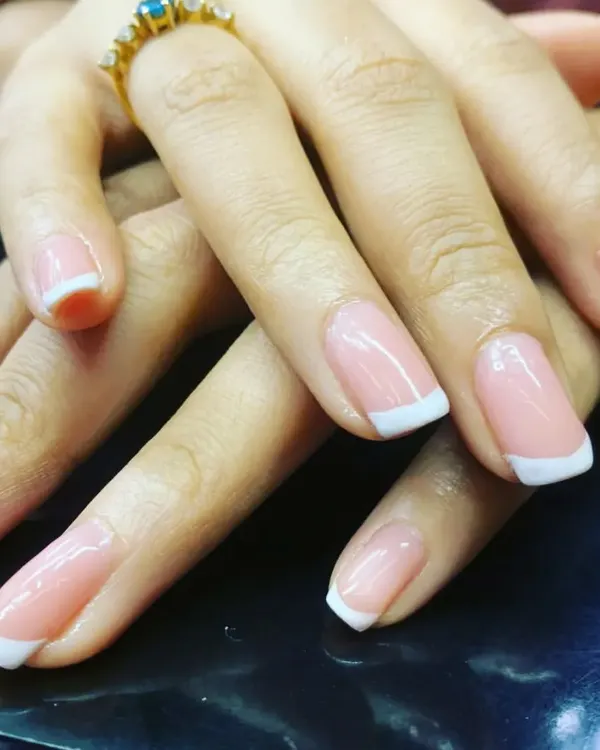 A flawless execution of the classic French manicure. This close-up highlights the perfectly shaped nails, the clean white tips, and the glossy finish that make this style a timeless favorite.