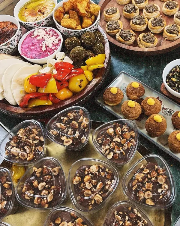 An abundant spread of our Mediterranean and Italian-inspired platters. This setup includes a mezze platter with falafel and hummus, mushroom vol-au-vents, a caprese board, and chocolate hazelnut mousse cups.