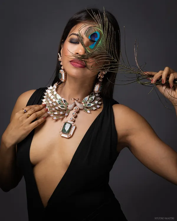 A creative and luxurious shot featuring a grand peacock-themed statement necklace. The use of a real peacock feather adds a layer of artistry to this high-end jewellery photograph.