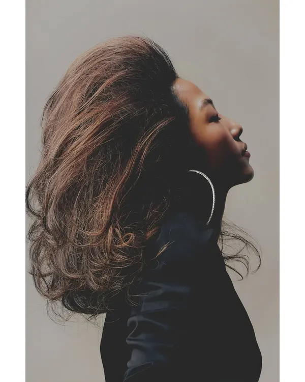 A profile shot from the 'Patricia' series, where the voluminous hair becomes a sculptural element. The lighting carves out the model's features, creating a powerful and elegant beauty portrait.