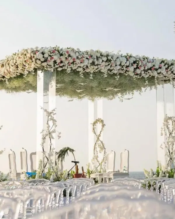 This all-white floral mandap set against the open sea is the definition of a dream wedding. I designed this to feel both grand and intimate, using transparent acrylic pillars so the structure wouldn't obstruct the beautiful ocean view, creating a serene and modern ceremony space.