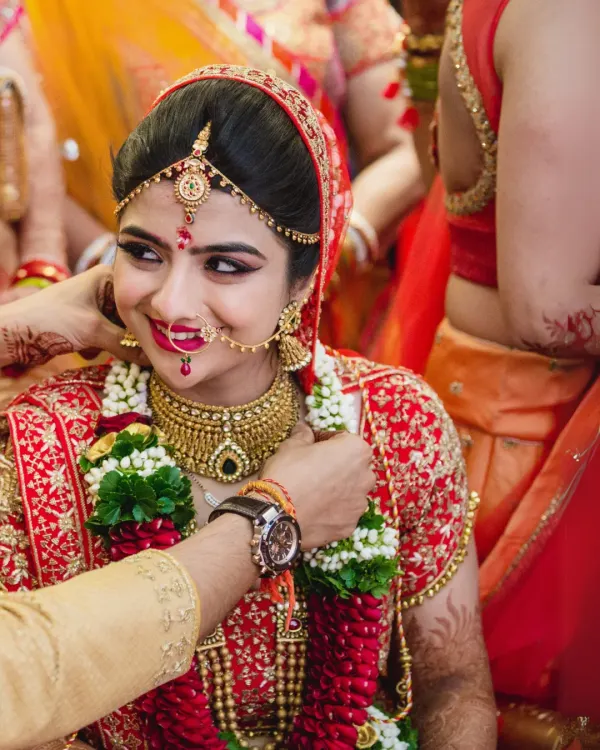 A candid moment during the wedding ceremony as the groom places the varmala on his smiling bride. Her expression of pure happiness is the focus of this beautiful shot.