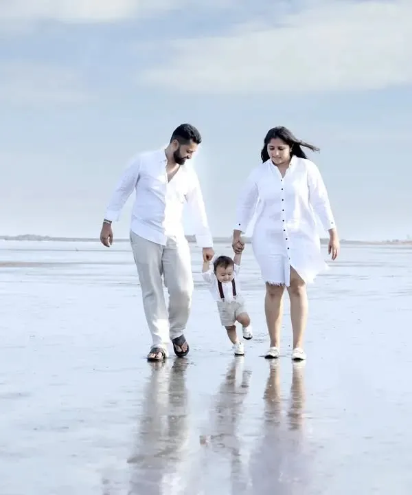 A family of three enjoying a walk on a serene Mumbai beach during their outdoor photoshoot. The natural, open environment allows for relaxed and authentic family portraits with beautiful reflections and light.
