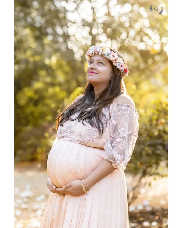 Bathed in warm, golden light, the mother-to-be looks up with a hopeful expression. This portrait, featuring one of my rental gowns and a floral tiara, captures the beautiful dream of motherhood.
