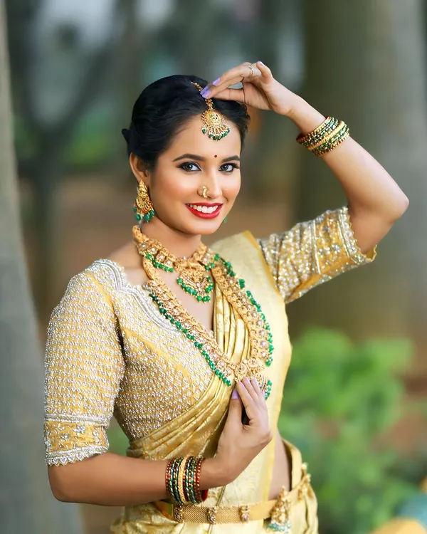 Feel like royalty in this classic golden Kanchi tissue saree. Paired with a heavily hand-embroidered blouse, this ensemble is a timeless choice for a South Indian wedding muhurtham.