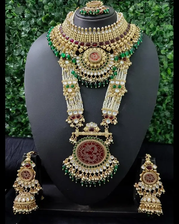 This is the ultimate statement of bridal luxury. A grand rental set featuring a detailed choker and a magnificent rani haar with red engraved pendants, green beads, and matching jhumkas.