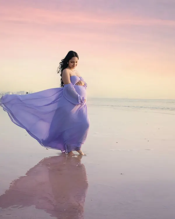 Walking on water. The lavender gown flows beautifully as the mother-to-be walks along the shoreline at sunset. The reflection on the wet sand and the pastel sky create a truly magical, painterly effect.