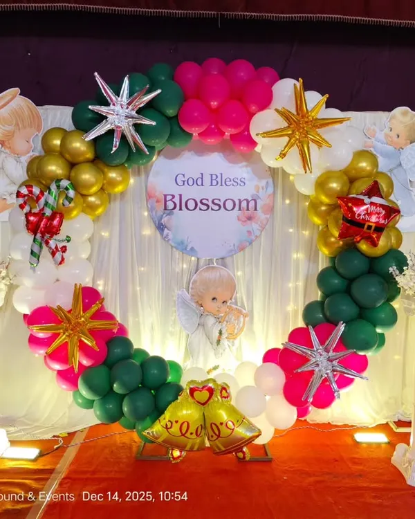 A unique Christmas-themed decoration for a Christening ceremony. The balloon ring backdrop includes festive colors, stars, angels, and other Christmas elements.