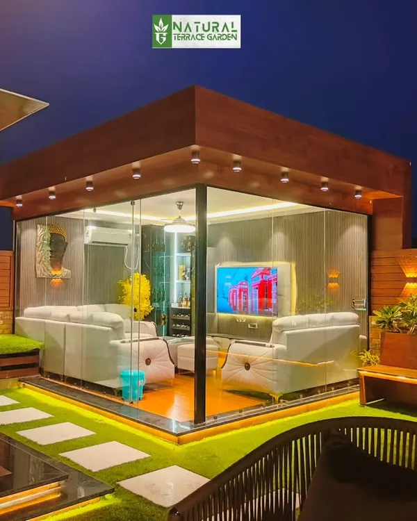 A stunning view of a completed terrace project in Shahdara, New Delhi, featuring a fully furnished, air-conditioned glass house. This structure provides a comfortable living space usable in any season, seamlessly connected to the open-air garden.