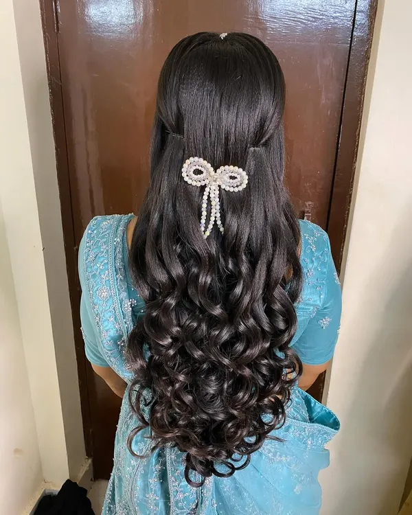 A stunning half-updo for a reception, featuring voluminous, perfectly defined curls. I added a beautiful pearl bow accessory to create a look that is both elegant and modern.
