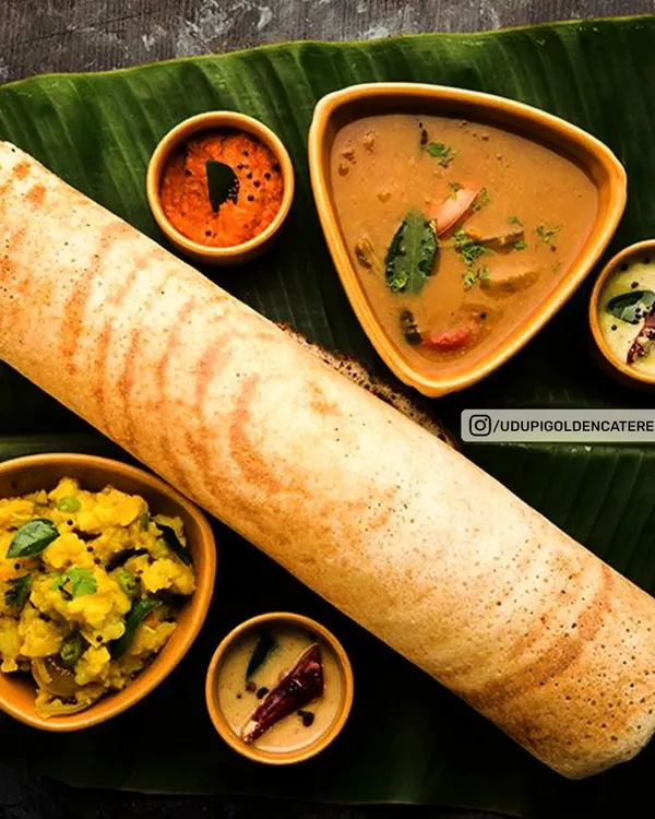 A perfectly crisp and golden Masala Dosa, served traditionally on a banana leaf. This iconic South Indian dish is a highlight of our live dosa counter, prepared fresh for your guests and served with flavorful sambar, coconut chutney, and potato masala.