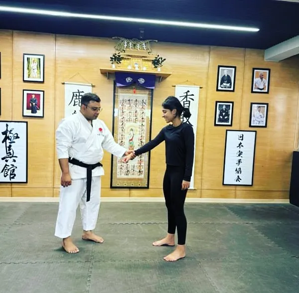 An instructor showing a technique to a female student. We are committed to empowering women through martial arts, fostering an environment of respect and strength.