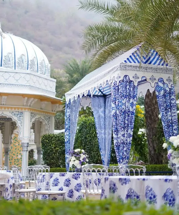 A stunning view of the event setup at The Leela Palace, Jaipur. The custom-designed canopy and tables, featuring blue and white prints, stand beautifully against the palace's architecture.