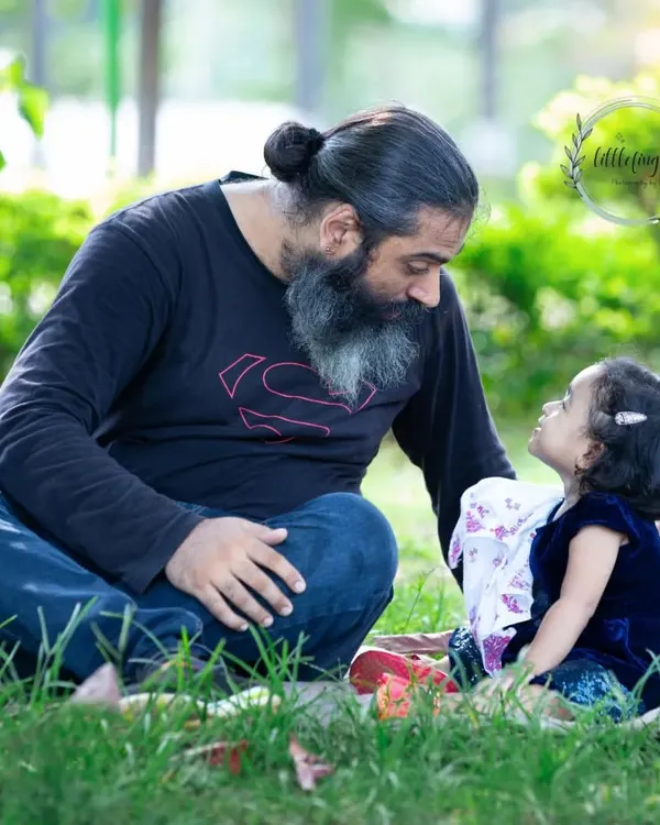 A father and his young daughter share a quiet, storytelling moment on a picnic blanket. The soft light and their focused expressions make this a truly precious memory.
