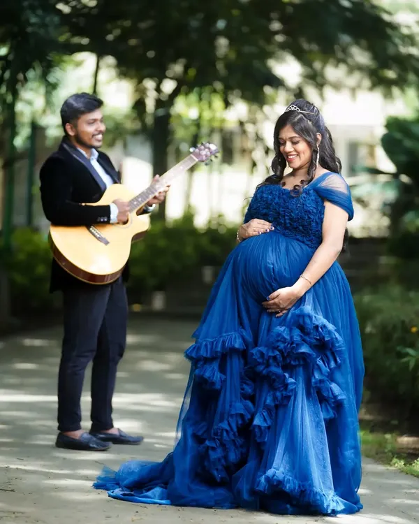 A creative maternity shoot where the father-to-be serenades his wife with a guitar. This photo tells a story and captures the love and anticipation of the couple in a beautiful outdoor setting.