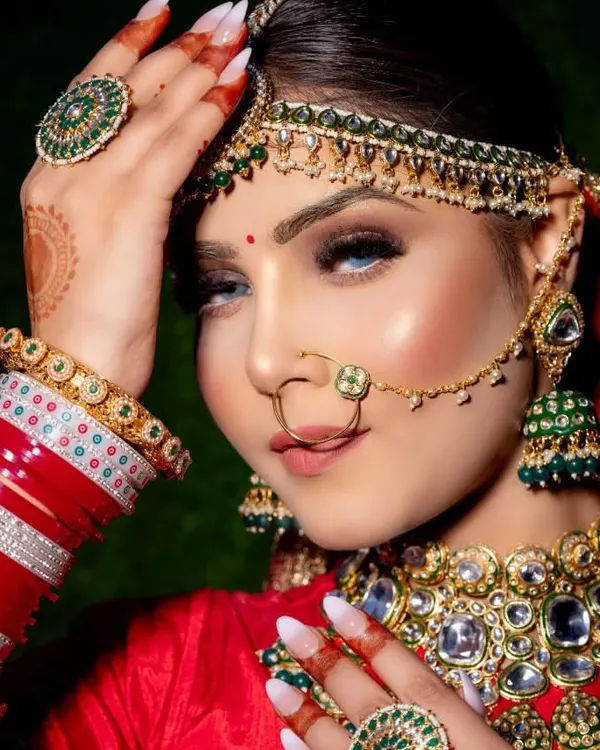 This is the quintessential classic bridal look I adore creating. The focus is on radiant skin, bold eyes defined with a sharp wing, and a timeless red lip, all framed by stunning kundan and emerald jewelry. It’s a look that feels both royal and deeply personal, perfect for the main wedding ceremony.
