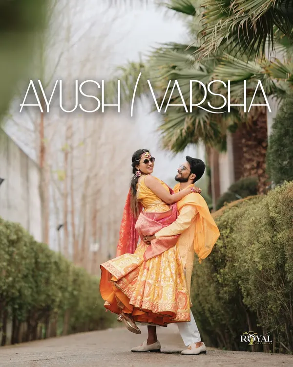 A joyful Haldi portrait, with the groom lifting the bride, both dressed in vibrant yellow outfits.