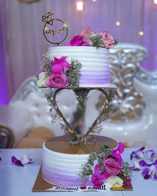 This beautiful two-tier engagement cake was a dream to create. The floating heart stand adds a touch of magic, and the fresh flowers in shades of purple and pink make it so romantic.
