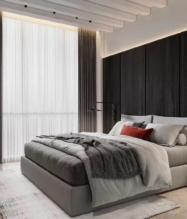A dark and moody bedroom design. The black wood-paneled feature wall creates a dramatic and cozy backdrop, while the sculptural red chair adds a vibrant pop of color and artistic flair.