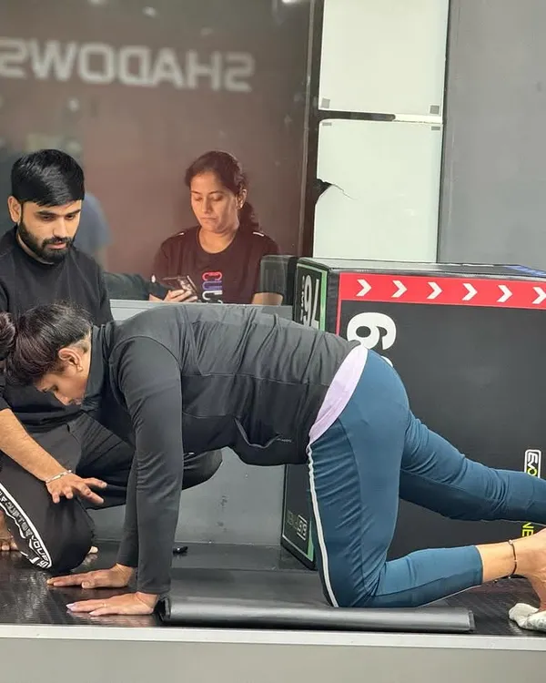 A trainer provides hands on guidance to a client during a core strengthening exercise, ensuring proper alignment and muscle engagement.