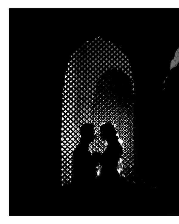 A stunning black and white silhouette of the couple against a latticed window. This artistic shot focuses on their form and connection, creating a timeless and romantic image.