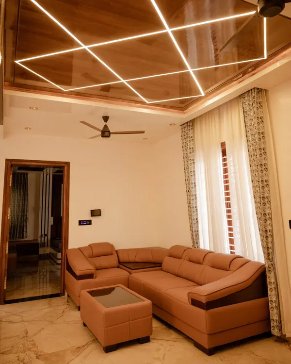 This living room features custom profile lighting integrated into a wooden ceiling panel. The geometric design creates a stunning visual centerpiece, while the automated curtains provide functional light control.